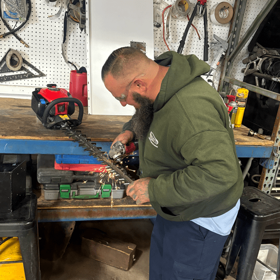 Man working with a power tool on a metal piece in a workshop.